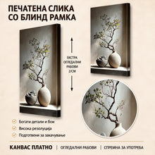 Вчитај ја сликата во галериски мод за гледање, Декоративна гранка со зелени листови во керамичка вазна, поставена покрај камена чинија со мазни камења.